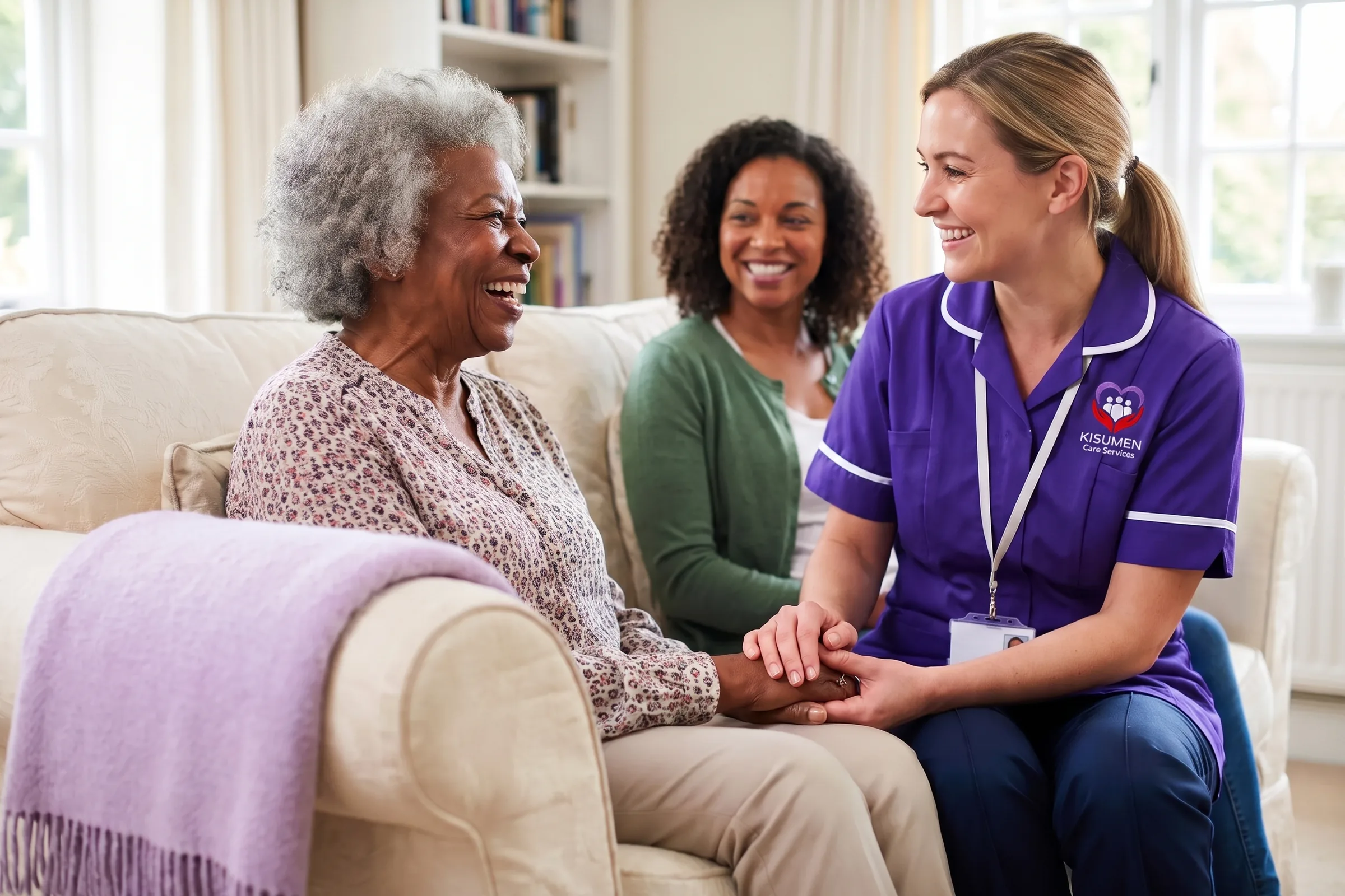 Elderly woman laughing with her Kisumen carer as her daughter smiles in the background